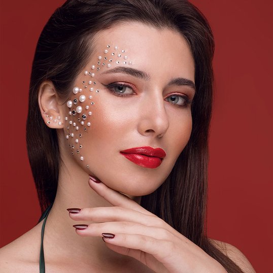 Modelo com batom vermelho e maquiagem com strass