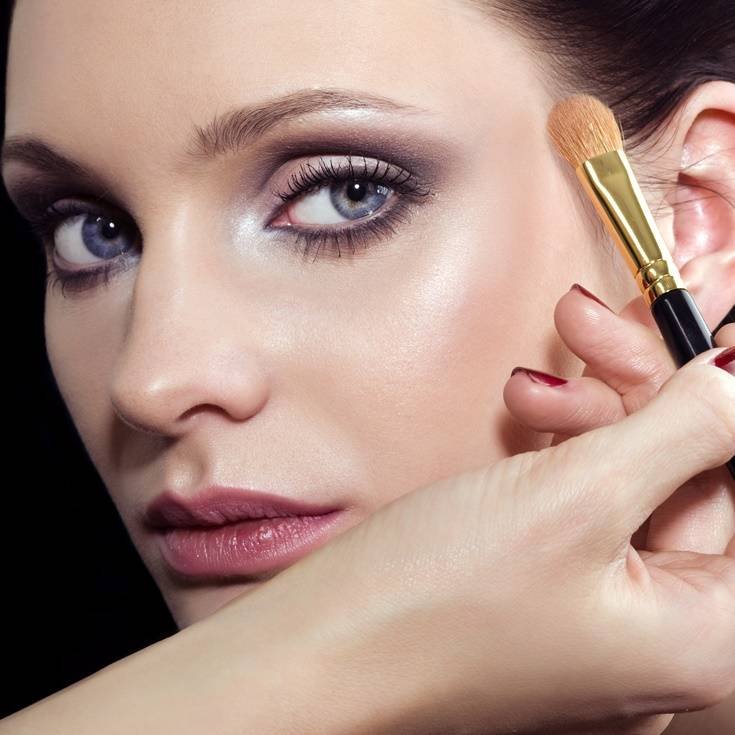 mulher usando pincel para depositar maquiagem na face
