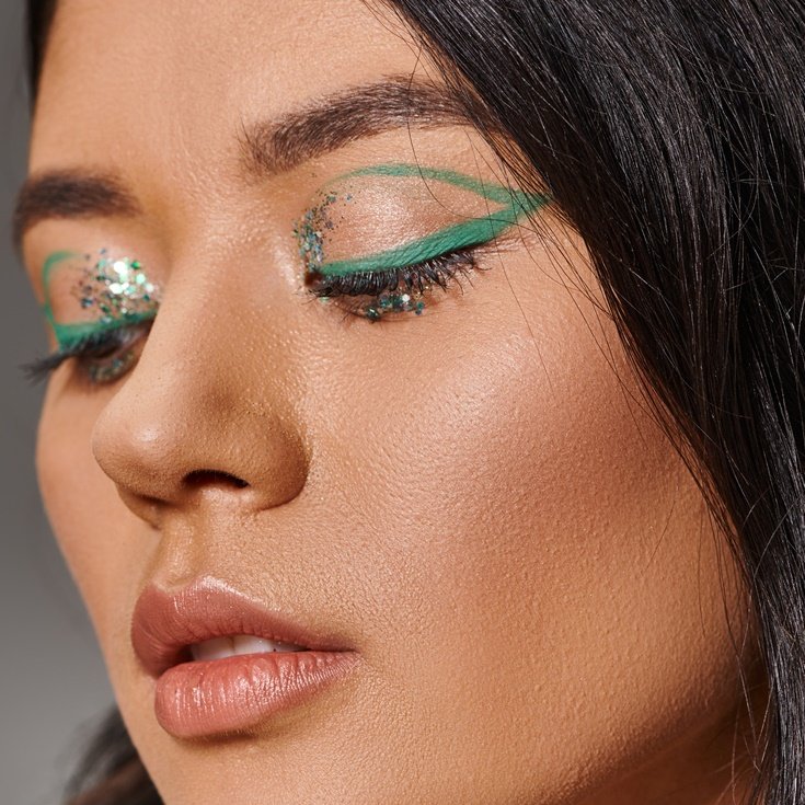 close de uma mulher usando delineador verde e glitter.