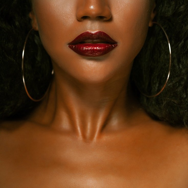 Detalhe de maquiagem para o ano novo com lábios em um intenso batom vermelho vinho e acabamento glossy, uma escolha elegante e clássica entre as cores do ano novo.