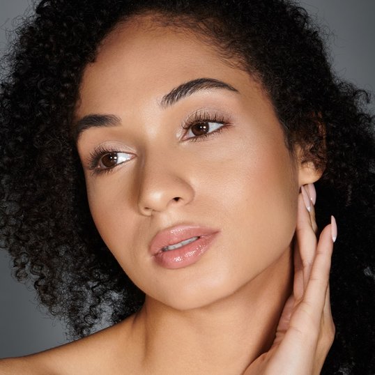 Foco em modelo com maquiagem simples, batom nude e máscara de cílios ultra volumosa.