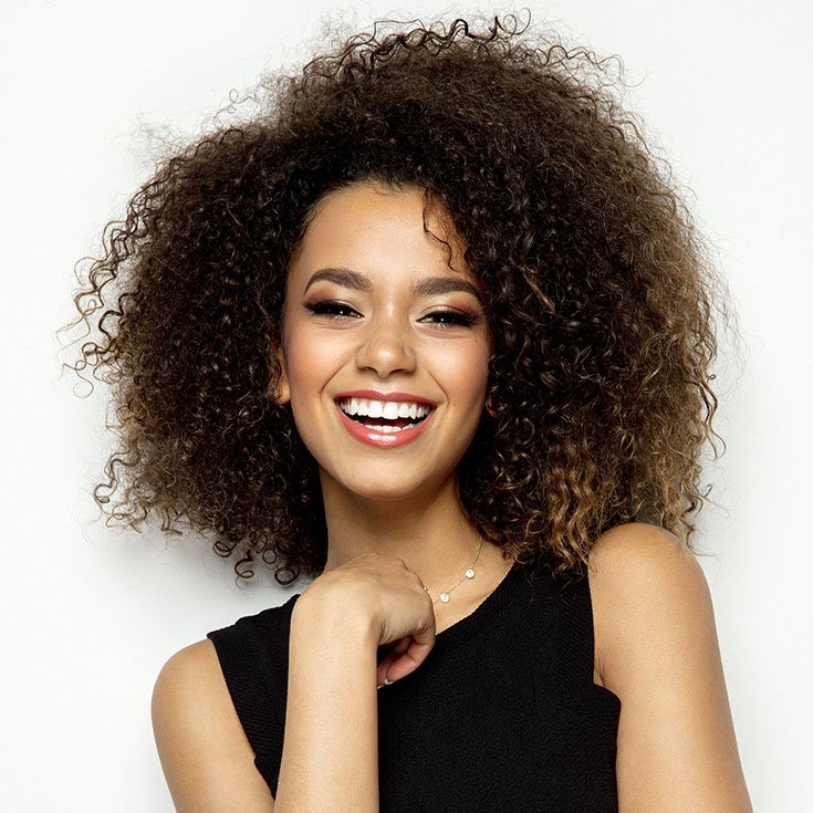 Mulher negra com cabelo cacheado e com maquiagem simples para a noite
