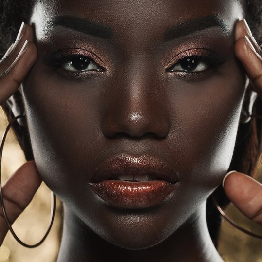 Mulher preta retinta usando maquiagem soft glam.