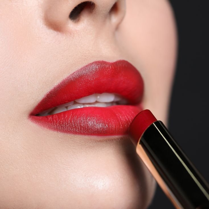 Boca usando batom vermelho com bordas mais escuras e centro com cor vermelho tomate dando um efeito ombré lips.