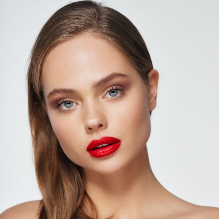 Mulher com olhos azuis usando batom vermelho intenso matte nos lábios.