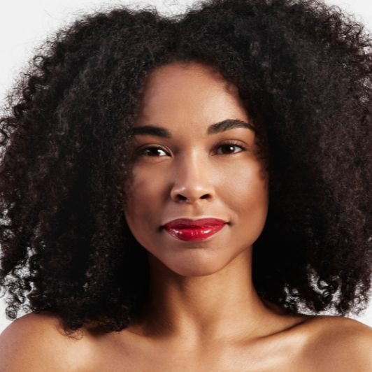 Mulher com cabelo cacheado e batom vermelho alaranjado nos lábios.