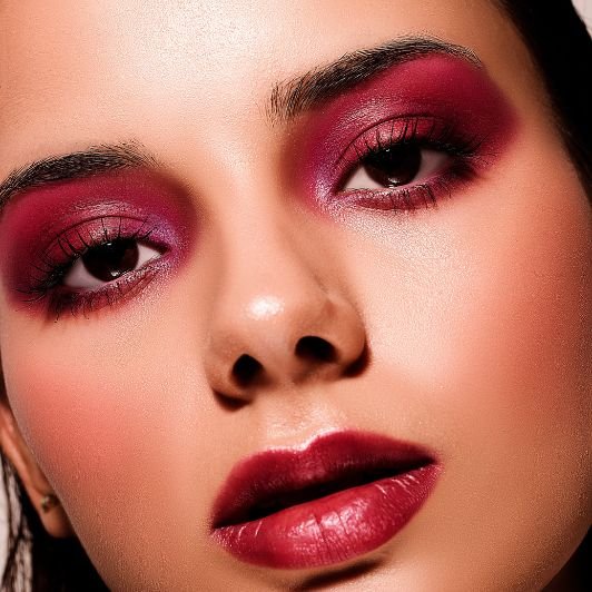 Mulher com sombra roxa nos olhos e batom vinho nos lábios.