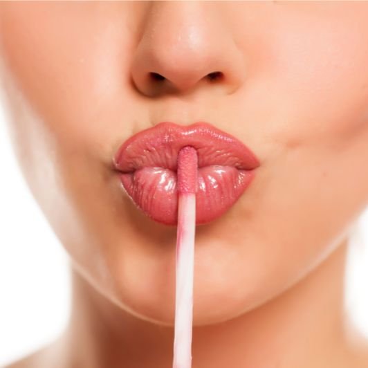 Mulher aplica gloss labial rosa para combinar com seu batom líquido