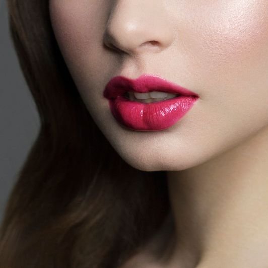 Boca com batom rosa cintilante.