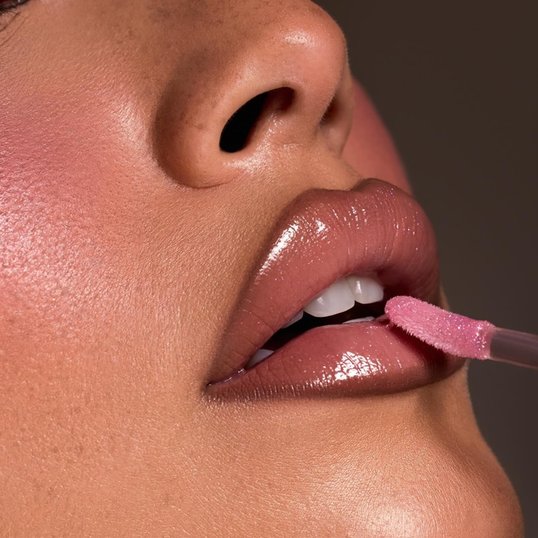 Mulher passando brilho labial nos lábios para completar seu Lip Combo.