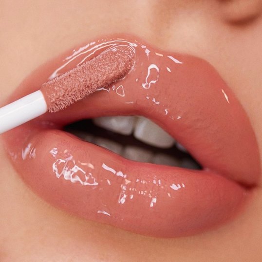 Aplicando lip oil com cor nos lábios.