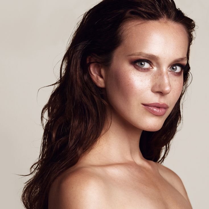 Menina com maquiagem colorida em tons escuros nos olhos e batom nude nos lábios.