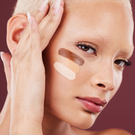 Mulher olhando para a câmera com três cores de base matte em seu rosto.