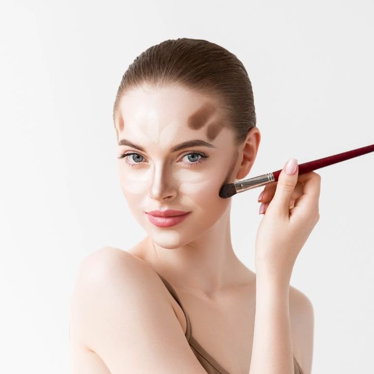 Mulher contornando seu rosto com contorno facial e iluminando com corretivo.