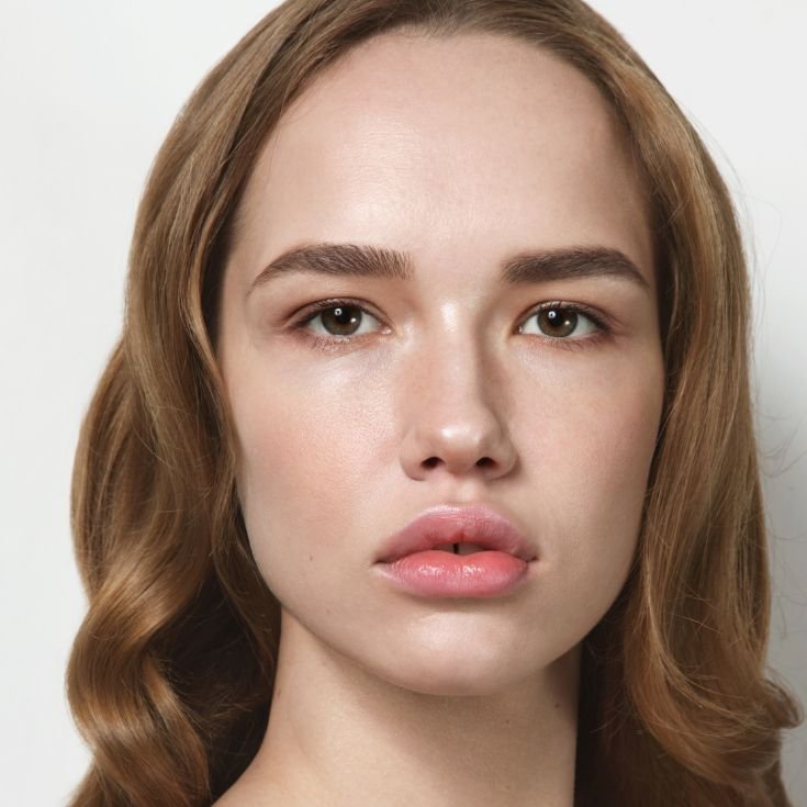 Menina olhando para a câmera com lábios rosados e cabelo loiro escuro