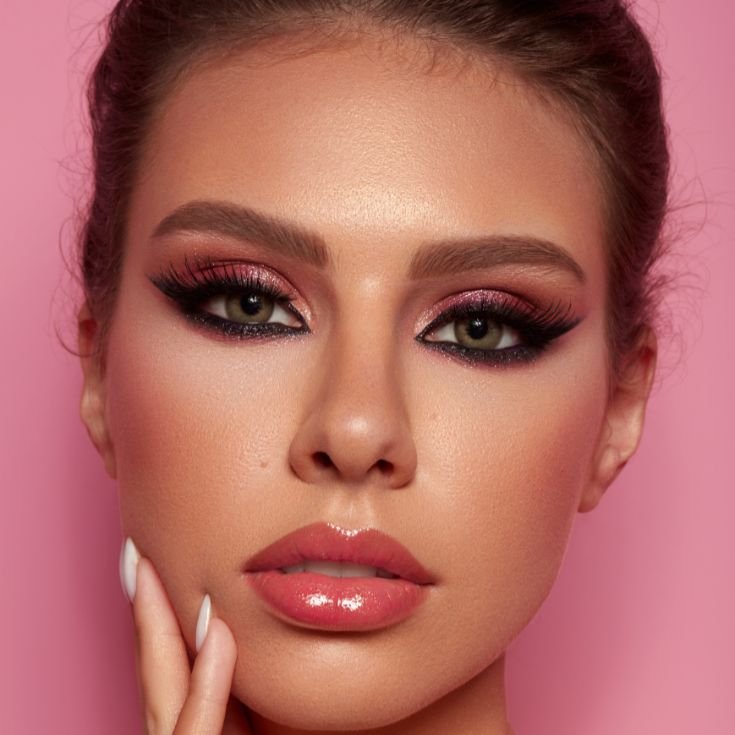 Mulher com olho esfumado e delineador nos olhos, lábios nude e blush marrom nas bochechas.