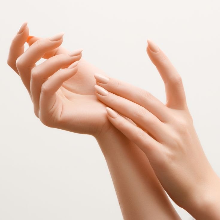 Mãos se tocando com esmalte nude.