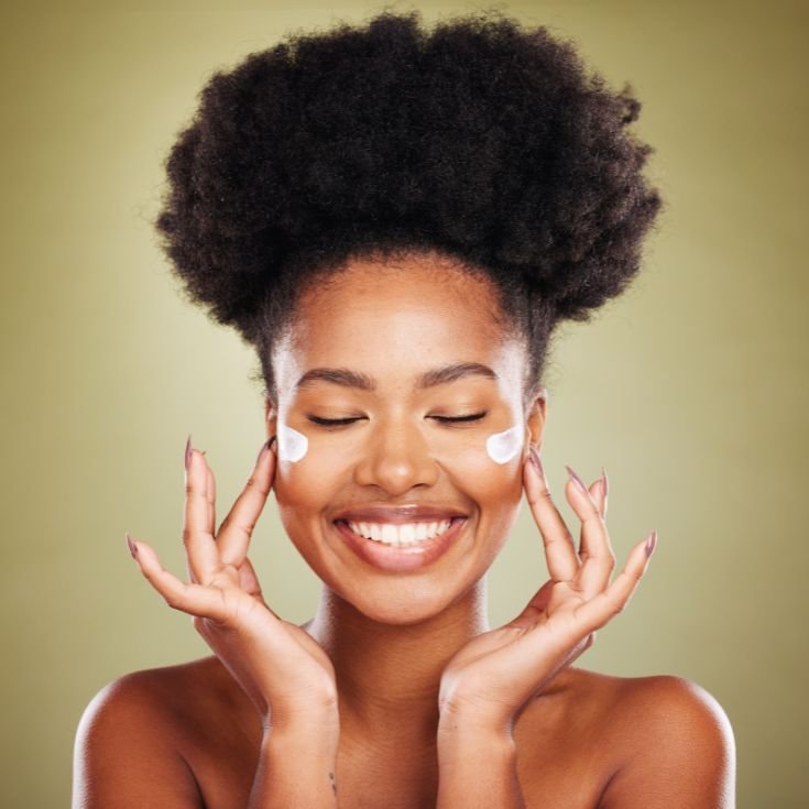 Mulher sorridente com protetor solar nas bochechas e dedos no rosto. 