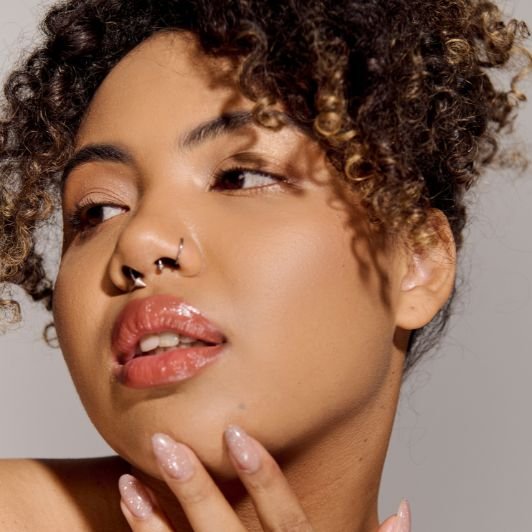 Mulher com a mão no queixo e maquiagem simples no rosto.