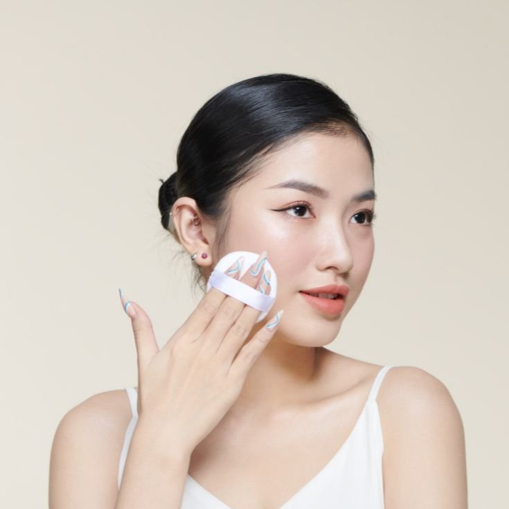 Coreana aplicando pó solto com esponja. 