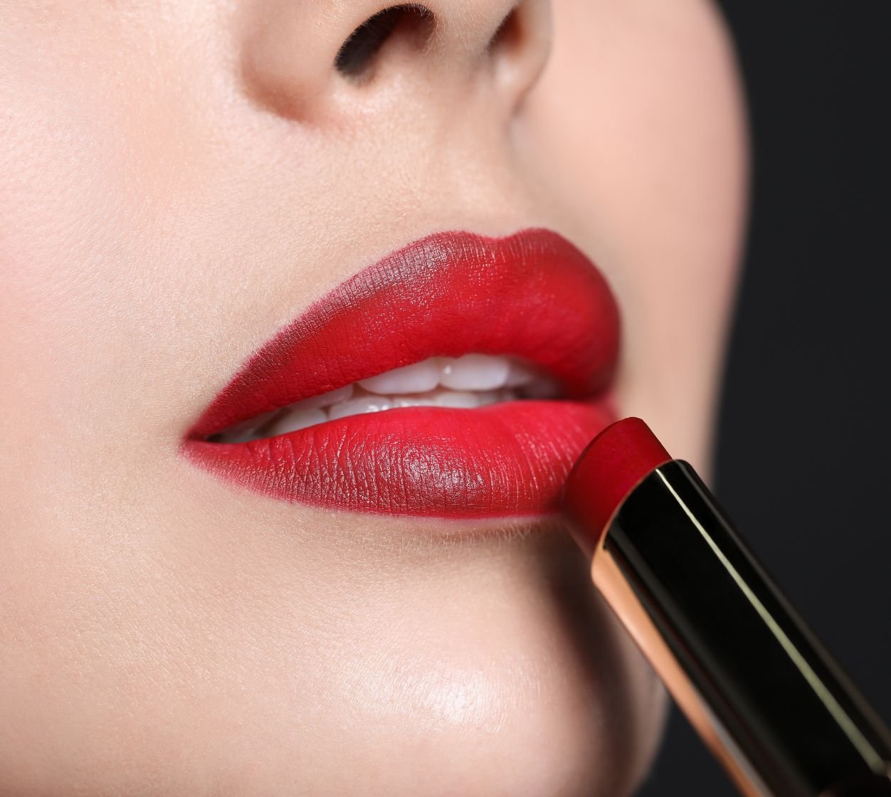 Boca usando batom vermelho com bordas mais escuras e centro com cor vermelho tomate dando um efeito ombré lips.