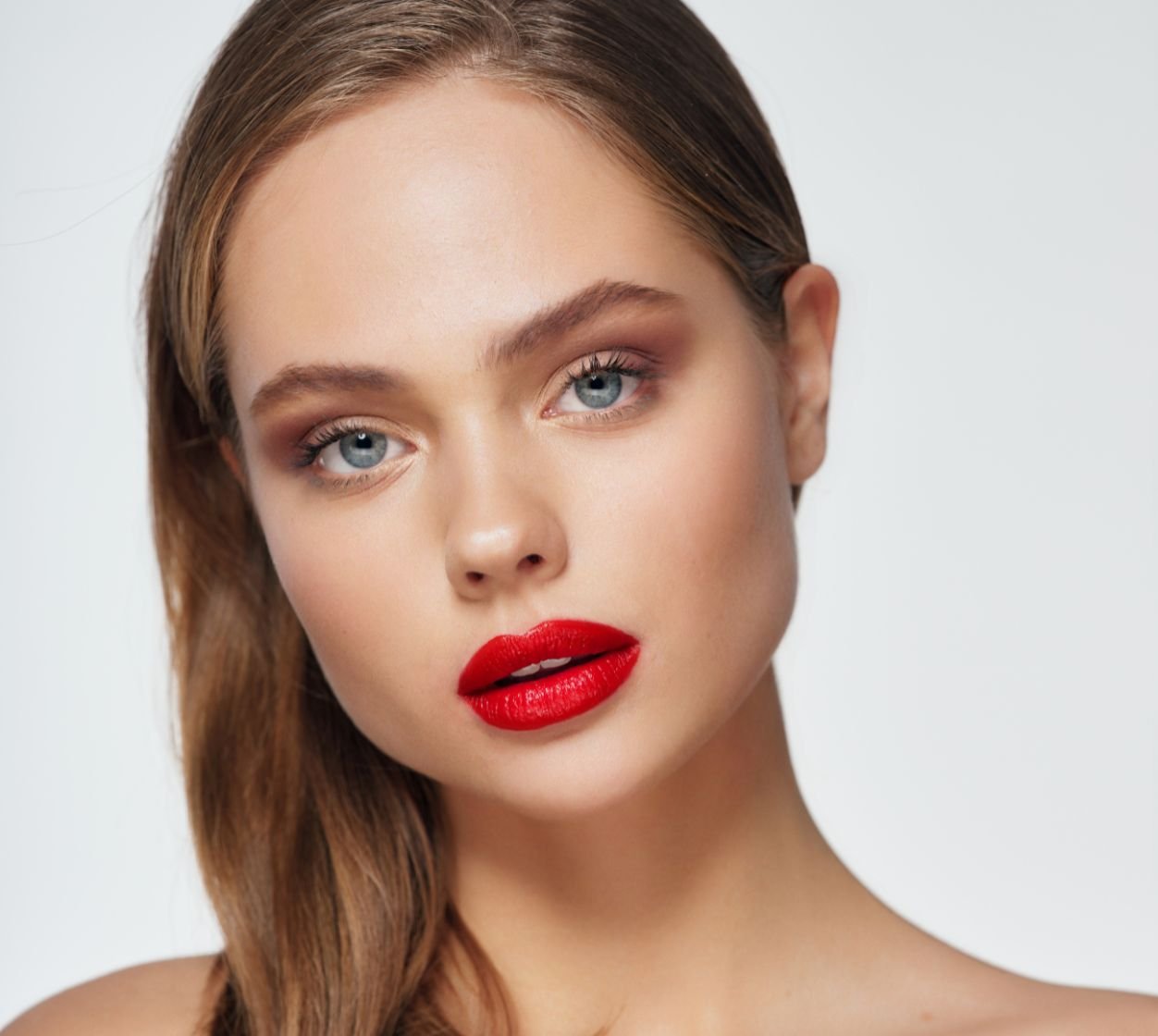 Mulher com olhos azuis usando batom vermelho intenso matte nos lábios.