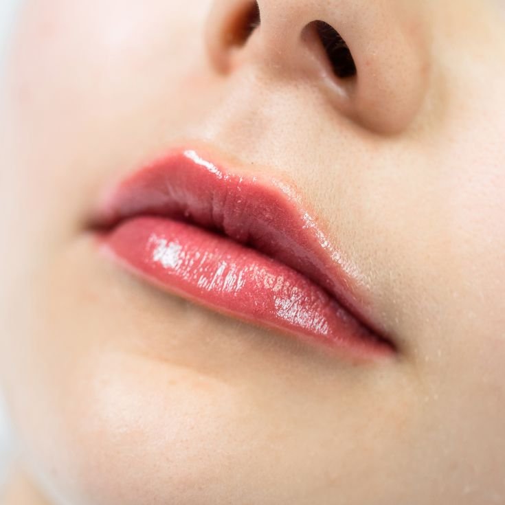 Boca de uma jovem mulher usando lip tint para colorir os lábios