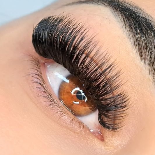 Mulher com olhos castanhos e extensão de cílios volume russo em seus cílios.