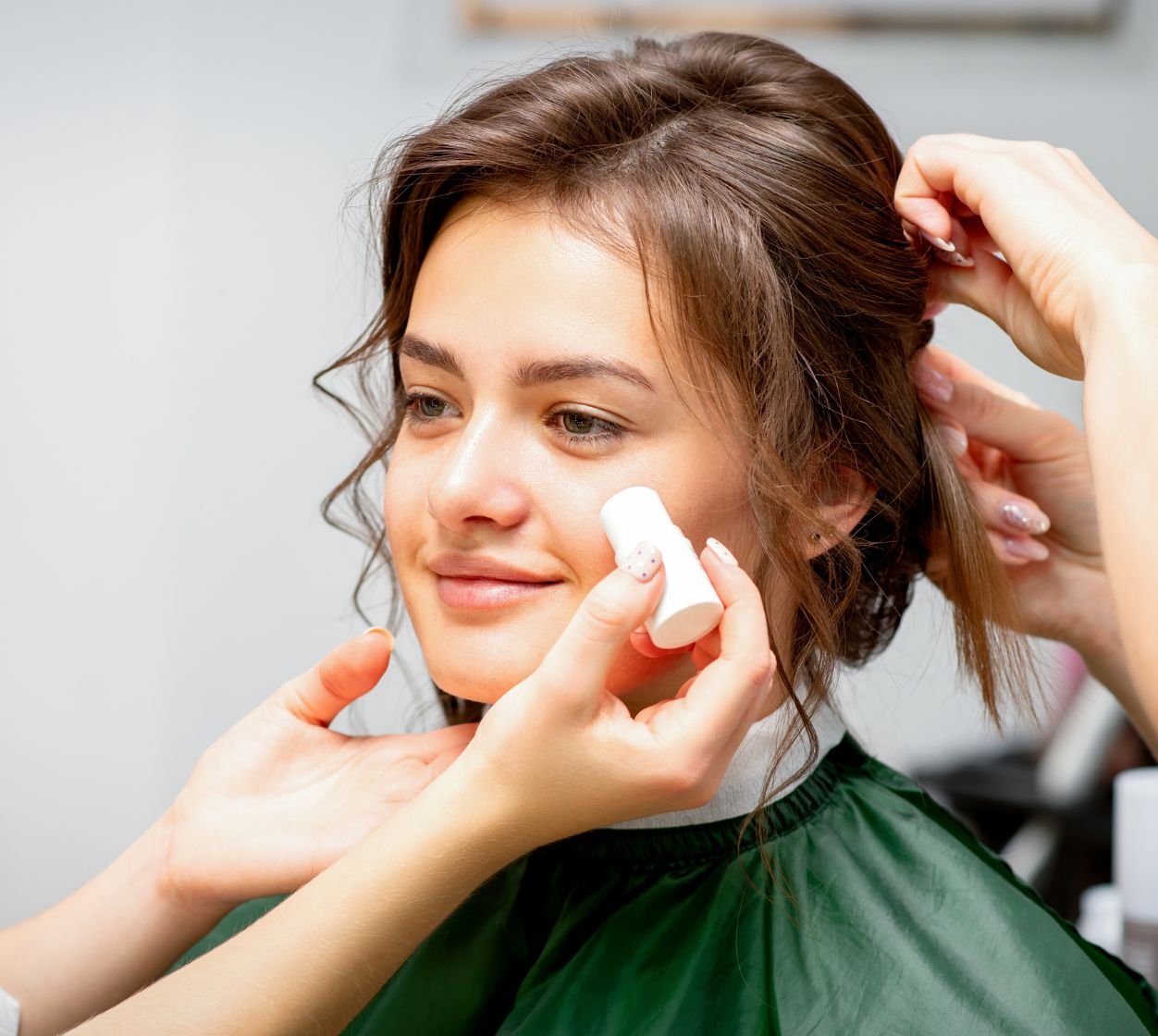 Maquiadora profissional aplica o blush em bastão no rosto de sua cliente