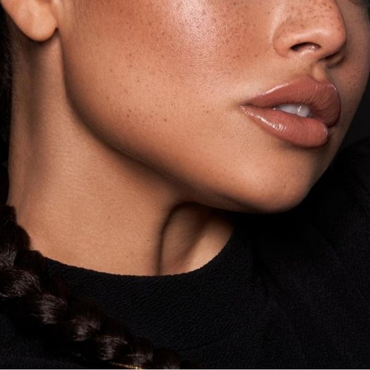 Parte inferior do rosto de uma mulher de pele morena com um blush natural em sua pele